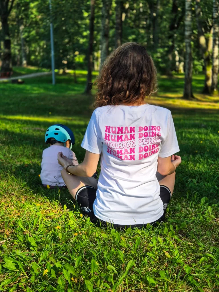 a woman meditating in mantra staples shirt with text that says human doing and human being